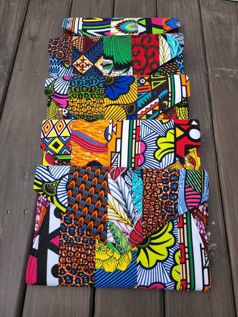 May include: A stack of five colorful fabric clutches with geometric and floral patterns. The clutches are made of a patchwork of different fabrics and are all different colors and designs.