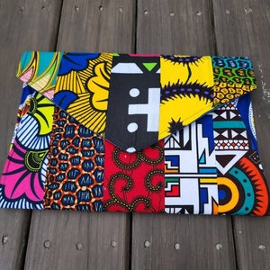 May include: A colorful clutch purse made from fabric with a patchwork design. The fabric is in various patterns and colors, including yellow, red, blue, green, and black.