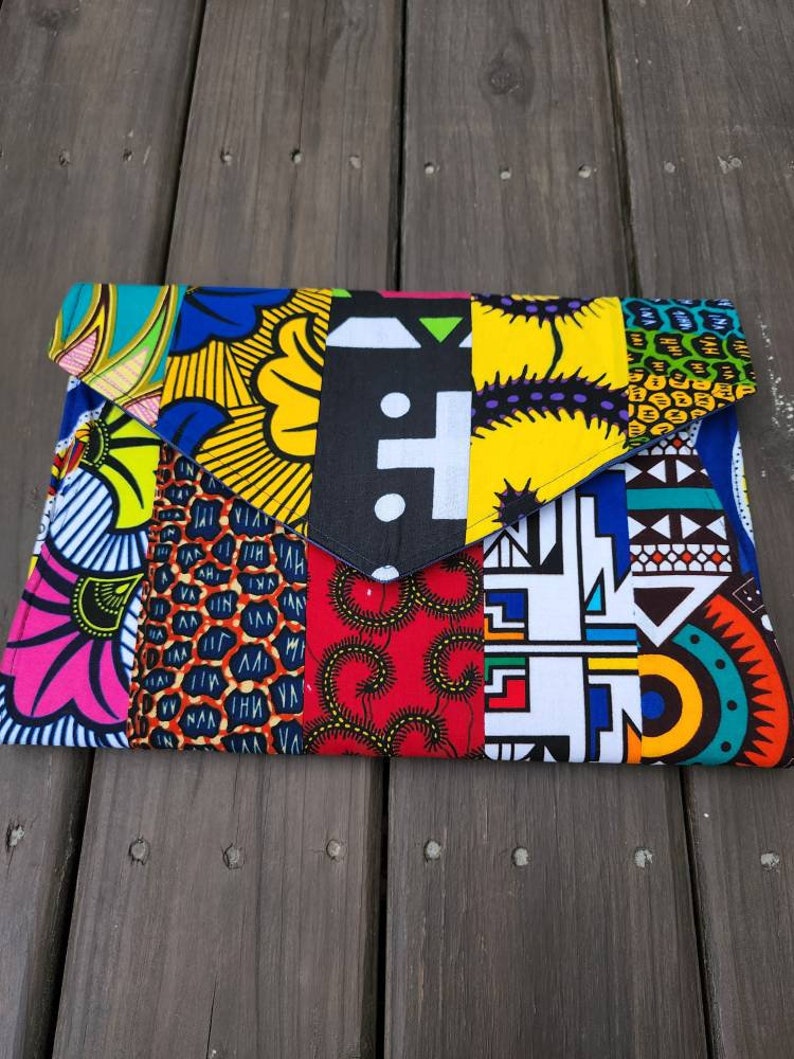 May include: A colorful clutch purse made from fabric with a patchwork design. The fabric is in various patterns and colors, including yellow, red, blue, green, and black.