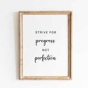 Puede incluir: Un cartel enmarcado con las palabras "STRIVE FOR progress NOT perfection" en escritura negra. El marco es de color marrón claro con un acabado envejecido, y el fondo es blanco.