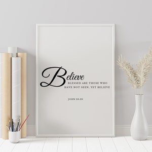 May include: White framed print with a black cursive word "Believe" and the text "Blessed are those who have not seen, yet believe" and "John 20:29".