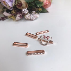 May include: Four rose gold-toned metal slider charms, one featuring a rhinestone-encrusted Mickey Mouse head with a pink bow, and three plain rectangular charms with rhinestone accents.
