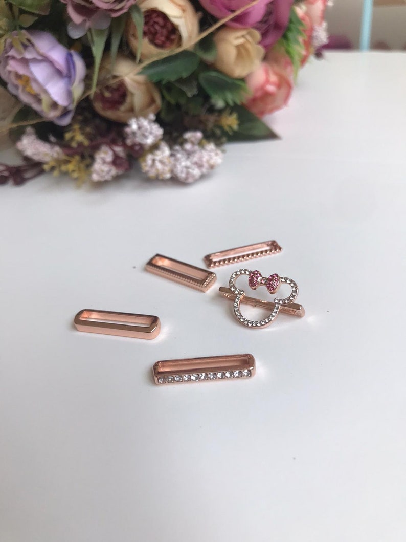 May include: Four rose gold-toned metal slider charms, one featuring a rhinestone-encrusted Mickey Mouse head with a pink bow, and three plain rectangular charms with rhinestone accents.