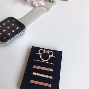 May include: A set of five gold-tone hair clips with rhinestones and a pink bow. The clips are displayed on a black velvet background.