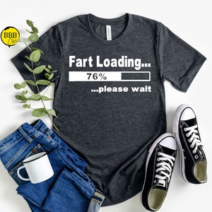 May include: A dark gray t-shirt with the text "Fart Loading... 76% ...please wait" printed in white.