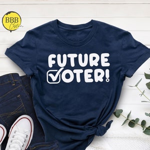 May include: A navy blue t-shirt with white text that reads "FUTURE VOTER!" with a checkmark in a box.