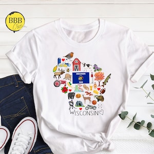 May include: White t-shirt with a heart-shaped design featuring various icons representing Wisconsin, including a red cardinal, a cow, a lighthouse, a cheese wedge, a beer stein, a football, and the Wisconsin state flag. The text "I &hearts; WISCONSIN" is written below the design.