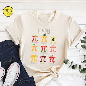 May include: A beige t-shirt with a graphic of different fruit pies with the text "PI MENU" and the mathematical symbol for pi above each fruit. The fruits include strawberry, pineapple, avocado, orange, watermelon, peach, banana, cherry, and apple.
