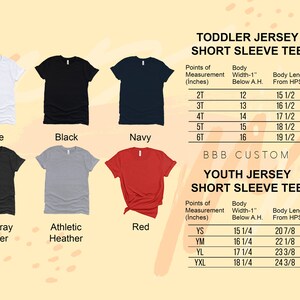 Op de afbeelding: Een tabel met maatvoeringen voor korte mouwen t-shirts voor peuters en jeugd. De tabel bevat de breedte van het lichaam, de lengte van het lichaam en de maatopties. De tabel wordt weergegeven tegen een achtergrond van verschillende gekleurde t-shirts.