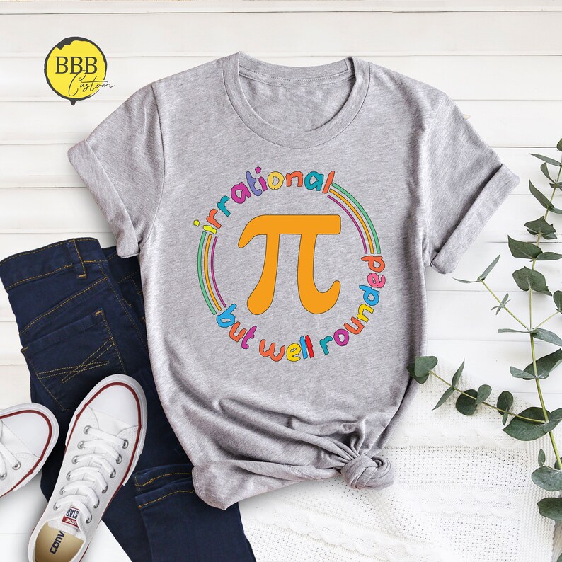 May include: A gray t-shirt with a colorful rainbow circle design featuring the mathematical symbol pi and the text "irrational but well rounded".