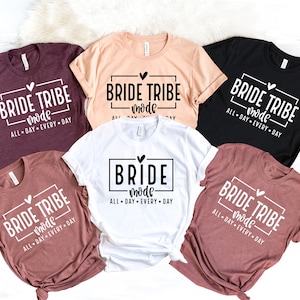 May include: Five t-shirts in different colors with the text "Bride Tribe Mode" and "All Day Every Day" printed on them. The shirts are arranged in a circle with the white shirt in the center.