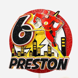 May include: Red, yellow, and black cake topper featuring The Flash superhero running with a lightning bolt. The topper includes a black number 6 and the name Preston.