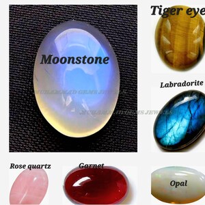 以下が含まれることがあります： ムーンストーン、タイガーアイ、ラブラドライト、ローズクォーツ、ガーネット、オパールなど、研磨された宝石の詰め合わせ。ムーンストーンは楕円形で、青と白の光沢があります。画像には「Moonstone」と「Muhammad Gems Jewels」の文字が含まれています。