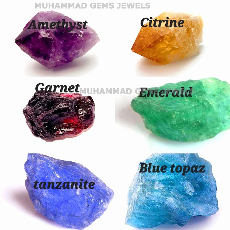May include: An assortment of raw gemstones, including amethyst, citrine, garnet, emerald, tanzanite, and blue topaz. Each stone is labeled with its name in a bold font. The gemstones vary in color, from deep purple to vibrant green and blue.