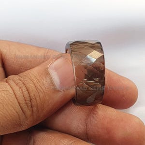 May include: A dark brown faceted gemstone ring. The ring is made from a single, large gemstone that is cut into a faceted shape. The gemstone is set in a simple band.