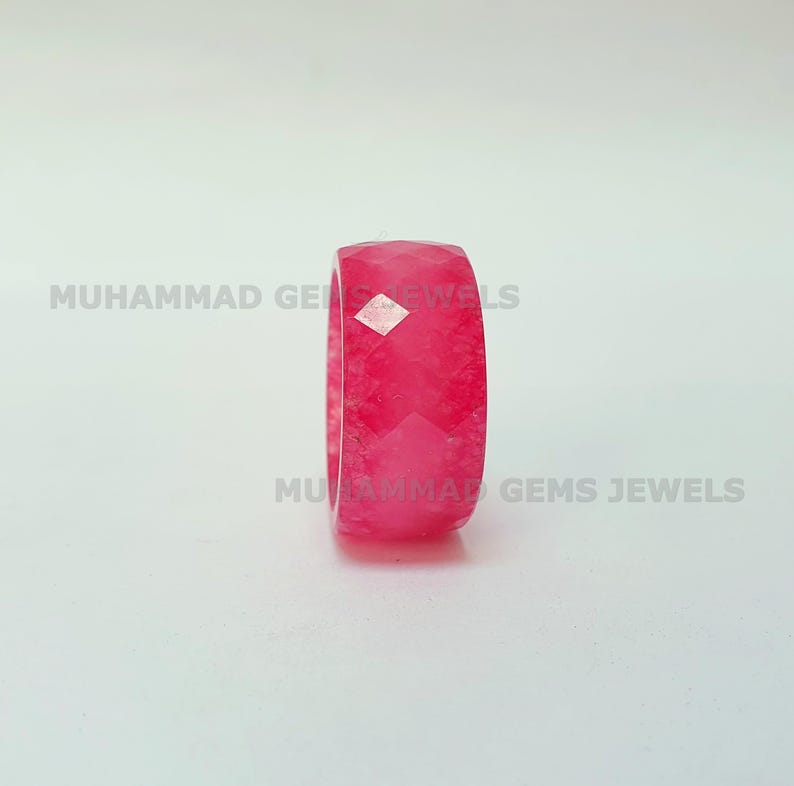 May include: A faceted, bright pink gemstone ring. The ring is a solid band with a geometric, multi-faceted design. The text "MUHAMMAD GEMS JEWELS" is printed on the image.