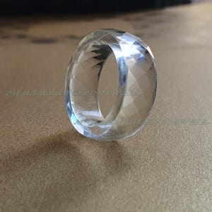 Può includere: Un anello di cristallo trasparente con un design sfaccettato. L'anello è realizzato in quarzo naturale e ha una finitura lucida.