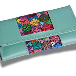 May include: A teal leather wallet with a colorful embroidered panel. The embroidery features a geometric pattern with pink, red, yellow, green, and blue threads.