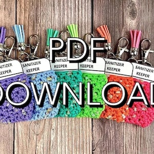 May include: Six colorful crocheted keychain holders for hand sanitizer bottles. Each holder has a white label that says "Sanitizer Keeper". The holders are attached to silver key rings with colorful tassels.