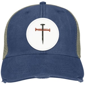Può includere: Un cappello da camionista blu e verde con una toppa bianca che presenta una croce nera con due chiodi rossi.