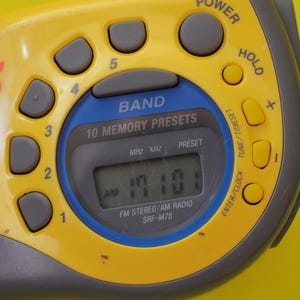 Puede incluir: Radio Sony Sports Walkman SRF-M78 amarilla y gris con pantalla digital que muestra la hora. Incluye botones preestablecidos, selector de banda y botones de encendido y retenci&oacute;n. Dise&ntilde;o retro.