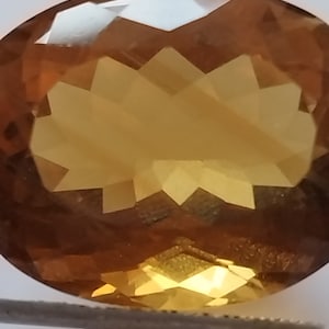 Peut inclure: Une grande pierre précieuse ronde et facetée de couleur brun doré. La pierre précieuse est taillée dans un motif géométrique complexe.