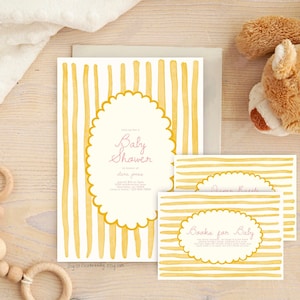May include: A yellow and white striped baby shower invitation with a pink script font that says "Baby Shower". The invitation has a scalloped oval shape with the text "Books for Baby" in a smaller oval shape.