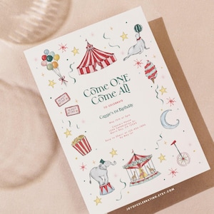 Puede incluir: Una tarjeta de invitación blanca con temática de circo, con ilustraciones de una carpa de circo, globos y un carrusel. El texto "Come One Come All" se muestra de forma destacada. La tarjeta está sobre un sobre marrón.