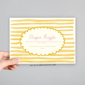May include: A yellow and white striped card with a scalloped circle in the center. The circle says "Diaper Raffle" in pink lettering and "Bring a pack of diapers in any size for a chance to win a prize." The bottom of the card says "JOY OF CELEBRATING. ETSY.COM".