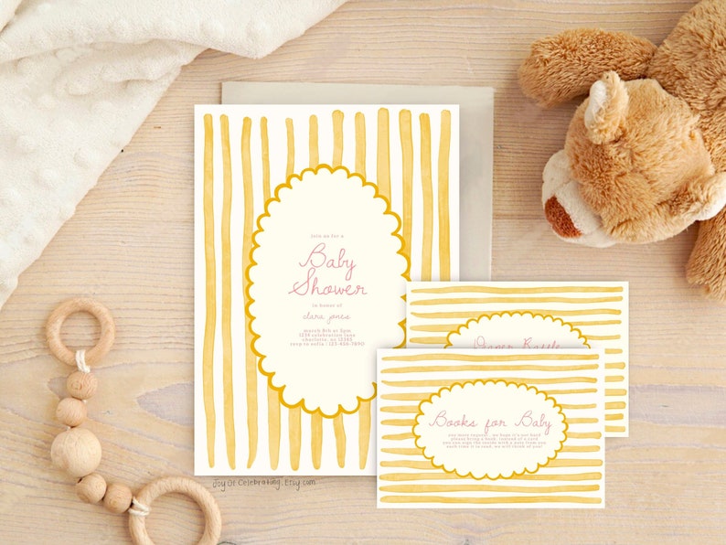 May include: A yellow and white striped baby shower invitation with a pink script font that says "Baby Shower". The invitation has a scalloped oval shape with the text "Books for Baby" in a smaller oval shape.