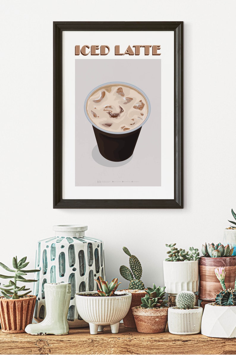 May include: A framed illustration of a glass of iced latte with the text "ICED LATTE" above the glass. The illustration is on a light gray background. The frame is black and the glass is clear with a brown liquid and ice cubes inside.