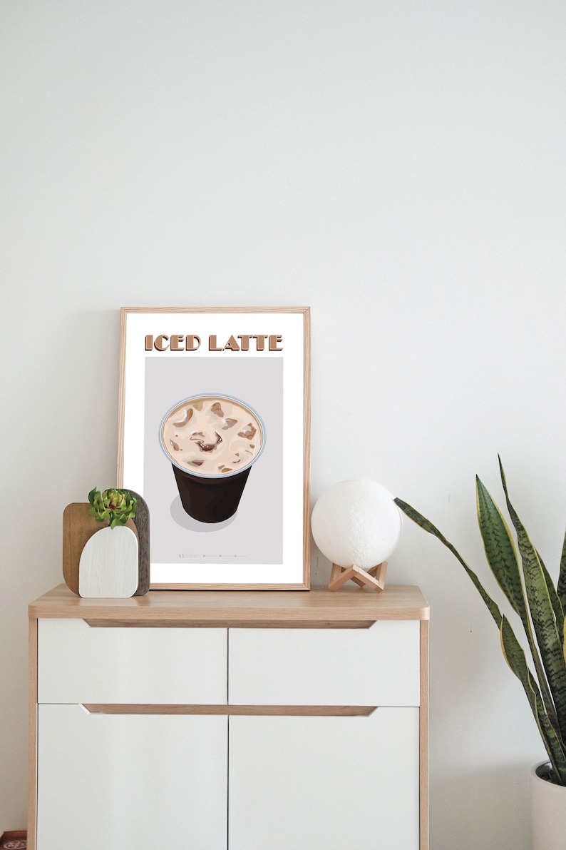 May include: A framed print with the text "ICED LATTE" in brown letters. The print features a cartoon illustration of a cup of iced coffee with ice cubes.