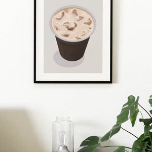 May include: A framed illustration of a brown iced latte in a clear plastic cup with ice cubes. The text "ICED LATTE" is printed in brown letters at the top of the frame.