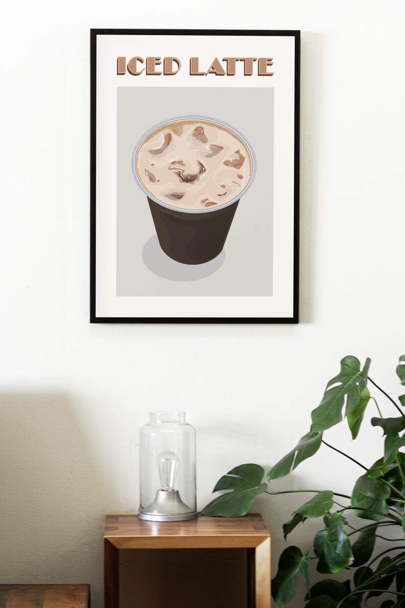 May include: A framed illustration of a brown iced latte in a clear plastic cup with ice cubes. The text "ICED LATTE" is printed in brown letters at the top of the frame.