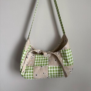 May include: A green and white checkered and paisley patterned fabric handbag with a single strap.