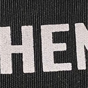 May include: Black fabric featuring the white words "THEY THEM THEIR" in a bold, sans-serif font. The text is displayed horizontally across the image.