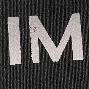 May include: Close-up of a black fabric with the words "HE HIM HIS" printed in white.