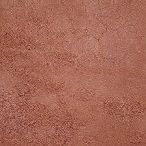 May include: A close-up of a textured, reddish-brown wall surface. The wall has a rough, uneven texture with subtle cracks and imperfections.