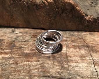 May include: A stack of silver rings with a hammered texture. The rings are stacked on top of each other and are arranged in a circle.