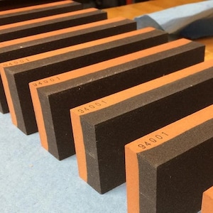 May include: A set of eight rectangular sharpening stones with a black and orange color scheme. Each stone has the number 940001 printed on it.