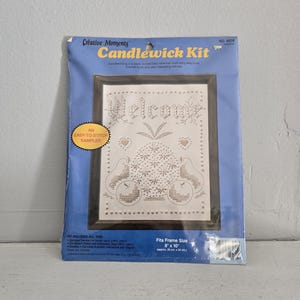 May include: A Candlewick Kit by Creative Moments, featuring an easy-to-stitch sampler design. The kit includes a framed design with the word "Welcome" and fruit illustrations. The frame size is 8" x 10".