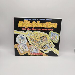 May include: A children's book titled The Magic School Bus and the Electric Field Trip by Joanna Cole and Bruce Degen. The black cover features a yellow school bus covered in lightning bolt patterns, along with various electrical illustrations.