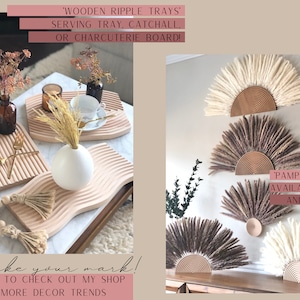 May include: Two wooden trays with a wavy design, one with a white vase and dried flowers, the other with a teacup and saucer. The trays are on a wooden table. On the right side of the image, three pampas grass sun wall decor pieces in white, brown, and beige. The text 'WOODEN RIPPLE TRAYS' and 'SERVING TRAY, CATCHALL, OR CHARCUTERIE BOARD!' is above the trays. The text 'PAMPAS GRASS SUN' is above the wall decor. The text 'AVAILABLE IN 4 SIZES AND 2 COLORS' is below the wall decor. The text 'Make your mark! BE SURE TO CHECK OUT MY SHOP FOR MORE DECOR TRENDS' is below the trays. The text 'MARK DESIGNS' is in the top right corner of the image.