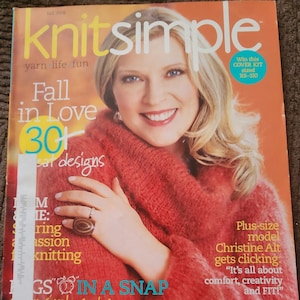 May include: Knitsimple magazine cover featuring a woman wearing a red knitted sweater. The cover text reads "Fall in Love 30+  Great Designs".