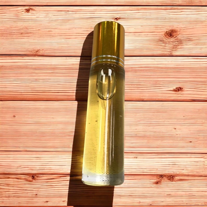 Pode incluir: Uma garrafa de vidro transparente com uma tampa dourada cheia de um l&iacute;quido amarelo claro. A garrafa est&aacute; sobre uma superf&iacute;cie de madeira.