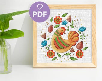 May include: Cross stitch pattern featuring a colorful chicken surrounded by flowers and leaves. The pattern is in a white frame with a light wood finish.