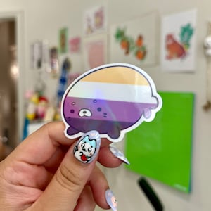 May include: A sticker of a cartoon bear with a purple, white, and yellow striped body. The bear has a holographic sheen and is holding a heart.