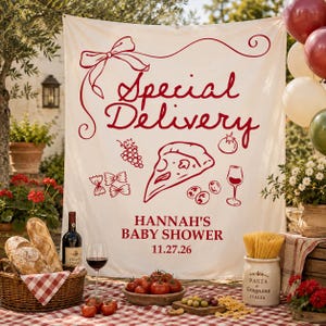 May include: A cream-colored fabric banner featuring red line art of a bow, a pizza slice, grapes, a tomato, olives, and a wine glass. The text reads Special Delivery, Hannah's Baby Shower, and 11.27.26 in a bold red serif and script font.