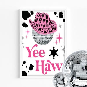 Puede incluir: Impresión enmarcada con un sombrero de vaquero rosa con un diseño de estampado de leopardo negro sobre una bola de discoteca. Las palabras "Yee Haw" están en rosa, con una insignia de sheriff negra y manchas de vaca. Bolas de discoteca adicionales en primer plano.