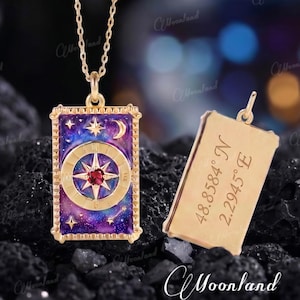 May include: A gold-toned rectangular pendant necklace featuring a purple and blue galaxy-themed enamel inlay with a central compass design, a small red stone, and celestial motifs. The reverse side is engraved with the coordinates 48.8584 N 2.2945 E.